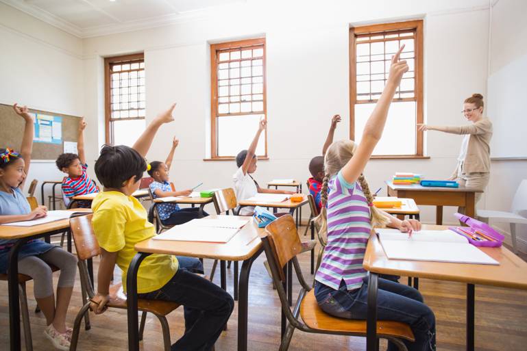 Pupils raising hand in classroom at the elementary school